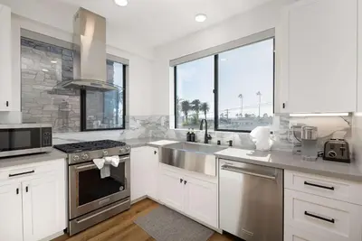 a kitchen with white cabinets and a stainless steel sink at Walk to the Beach & Pier Ocean View Roof Deck in Oceanside