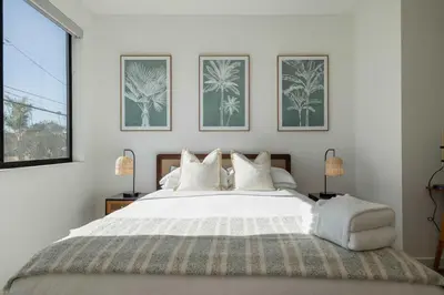 a bedroom with a large white bed with three pictures on the wall at Walk to the Beach & Pier Ocean View Roof Deck in Oceanside