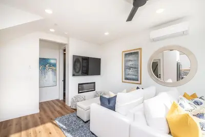 a white living room with a white couch and a mirror at Ocean View Roof Deck - Walk to the Beach & Pier in Oceanside