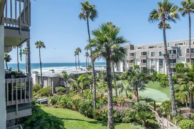 a view of a hotel with palm trees and the ocean at Walk to the Beach Sunset Ocean Views - D-207 in Oceanside