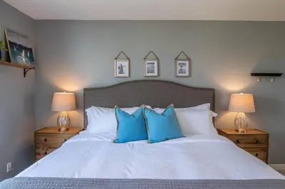 a bedroom with a white bed with blue pillows at Walk to the Beach Sunset Ocean Views - D-207 in Oceanside