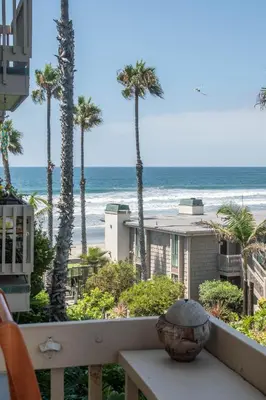 a balcony with a view of the beach and palm trees at Walk to the Beach Sunset Ocean Views - D-207 in Oceanside