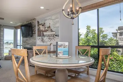 a dining room with a table and chairs and windows at Panoramic Water Views - Steps to the Beach - F-2 in Oceanside