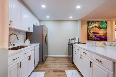 a kitchen with white cabinets and a stainless steel refrigerator at Panoramic Ocean Views Beach & Boardwalk Access in San Diego
