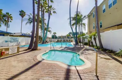 a swimming pool with palm trees next to a building at Panoramic Ocean Views Beach & Boardwalk Access in San Diego