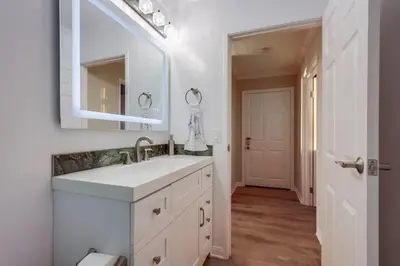 a white bathroom with a sink and a mirror at Panoramic Ocean Views Beach & Boardwalk Access in San Diego