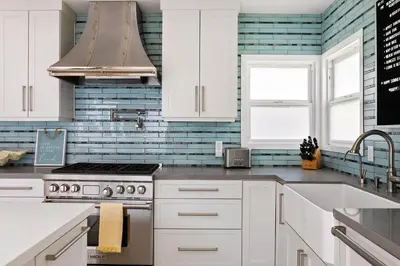 a kitchen with white cabinets and blue subway tiles at Inviting 3BR Near Mission Beach in San Diego