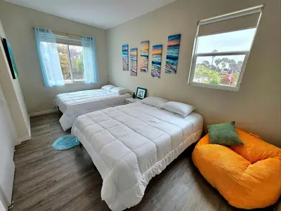 a bedroom with two beds and an orange chair at Heights Golden Luxe Retreat in San Diego