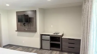 a bedroom with a desk and a tv on the wall at Broadway Inn and Suites in Chula Vista