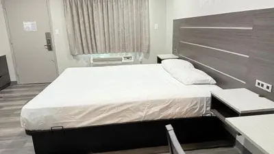 a bedroom with a large bed with a wooden headboard at Broadway Inn and Suites in Chula Vista