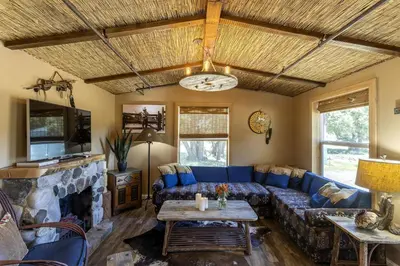 a living room with a blue couch and a fireplace at Unique Western-Themed Cabin Rental for Secluded Getaway in Warner Springs, California in Warner Springs