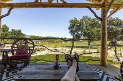 a person with their feet up on a wooden table on a porch at Unique Western-Themed Cabin Rental for Secluded Getaway in Warner Springs, California in Warner Springs