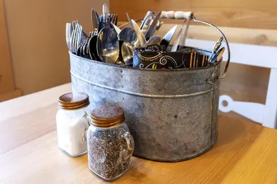 a bucket of utensils sitting on top of a table at Unique Western-Themed Cabin Rental for Secluded Getaway in Warner Springs, California in Warner Springs