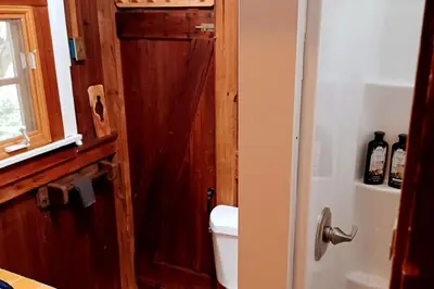 a bathroom with a toilet and a wooden door at Historic Holiday Redwood Cabin in Palomar Mountain, California in Palomar Mountain