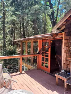 a cabin with a wooden deck with a glass door at Historic Holiday Redwood Cabin in Palomar Mountain, California in Palomar Mountain