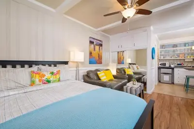 a bedroom with a blue bed and a living room at Steps to Newport Harbor Balboa Fun Zone Dock Access Edgewater Studios in Newport Beach