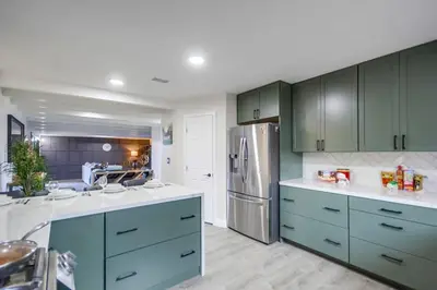 a kitchen with green cabinets and a stainless steel refrigerator at Entire Private Home with 3 Bedrooms 2 Bathrooms, Gated Yard, 100 inch TV, 1 Gbps WiFi, Available Now in San Diego