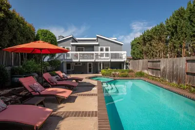 a pool with chairs and an umbrella next to a house at Bird Rock Dream - Pool, Spa, and Stunning Ocean View! in San Diego