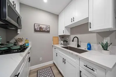 a kitchen with white cabinets and a sink and a stove at Entire Private Studio with 1 King Bed, Full Kitchen, Gated Yard, Available Now in Spring Valley