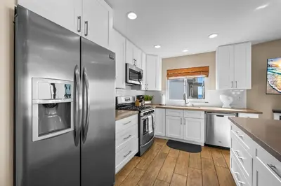 a kitchen with white cabinets and a stainless steel refrigerator at Oceanview Steps to Beach AC Parking! in Newport Beach