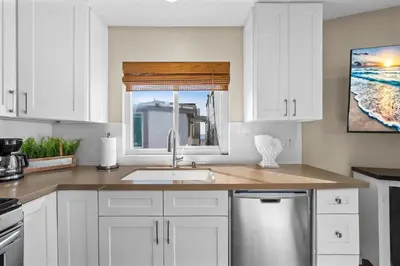 a kitchen with white cabinets and a sink and a window at Oceanview Steps to Beach AC Parking! in Newport Beach