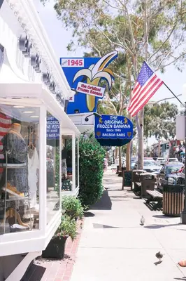 a store with an american flag on a sidewalk at Oceanview Steps to Beach AC Parking! in Newport Beach