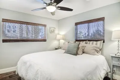 a bedroom with a white bed with a ceiling fan at Steps to SandParkingACGround Level in Newport Beach