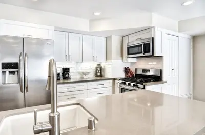 a kitchen with white cabinets and a stainless steel refrigerator at Steps to SandParkingACGround Level in Newport Beach