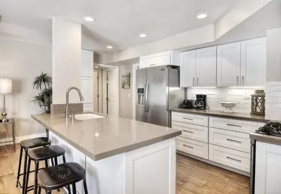 a kitchen with white cabinets and a kitchen island with stools at Steps to SandParkingACGround Level in Newport Beach