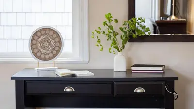 a black dresser with a lamp and a vase with books at The Edgewater Condos by AvantStay in Newport Beach