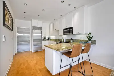 a kitchen with white cabinets and a counter with chairs at Pool, Hot Tub, Steps To Omni La Costa in Carlsbad