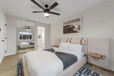 a bedroom with a bed with a ceiling fan at 2BR, 2B, Coffee Bar, Cozy Sectional, Rainfall Shower, Smart TVs, Cozy Beach Theme in San Diego