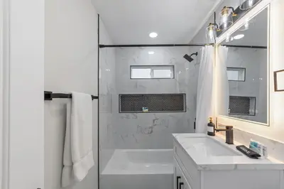a white bathroom with a shower and a sink at 2BR, 2B, Coffee Bar, Cozy Sectional, Rainfall Shower, Smart TVs, Cozy Beach Theme in San Diego