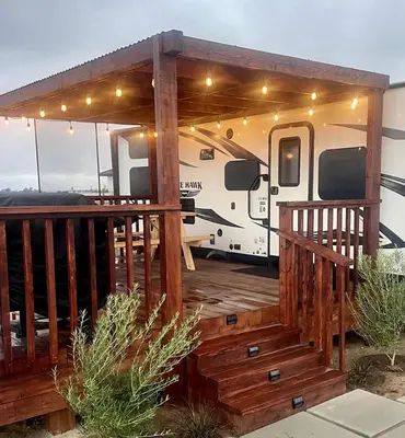 a rv with a deck with awning and lights on it at Cozy Camper with Fire Pit and Beautiful Sunsets in California in Temecula