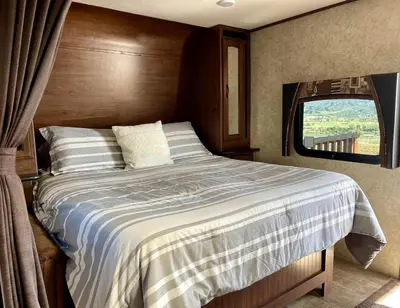 a bedroom with a large bed with a window at Cozy Camper with Fire Pit and Beautiful Sunsets in California in Temecula