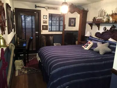 a bedroom with a bed with a blue striped comforter at Grand Rustic Cabin Rental with Private Hot Tub near Escondido, California in Julian