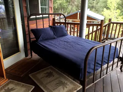 a bed on the porch of a house at Grand Rustic Cabin Rental with Private Hot Tub near Escondido, California in Julian