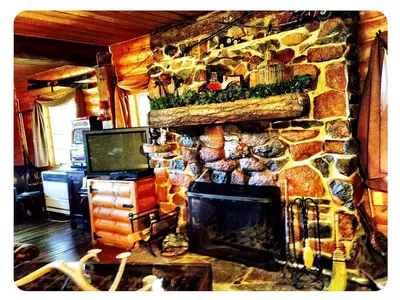 a stone fireplace in a living room with a tv at Grand Rustic Cabin Rental with Private Hot Tub near Escondido, California in Julian