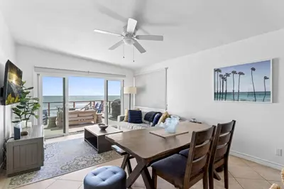 a living room with a dining table and a view of the ocean at Private beach toes on the Sand Waterworld in Dana Point
