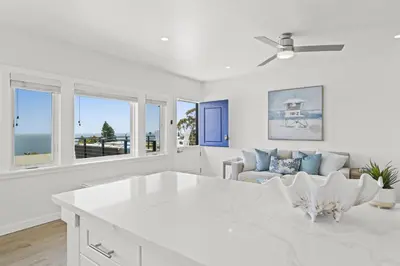 a white living room with a couch and a table at Penthouse Steps from Victoria Beach 180 degree ocean views in Laguna Beach