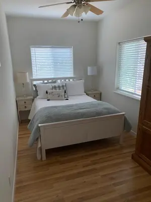 a bedroom with a bed with a fan and two windows at Rustic Ridge Vineyards Cottage in Jamul