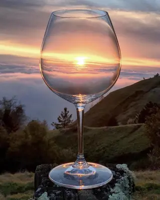 a wine glass sitting on a table with the sunset at Rustic Ridge Vineyards Cottage in Jamul