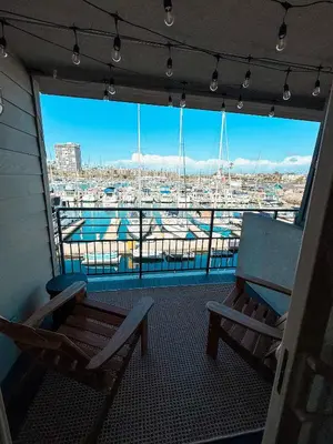 a balcony with two chairs and a view of a harbor at Fully Renovated Beachfront Surf House Oceanside in Oceanside