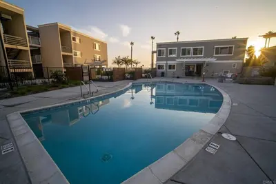 a large swimming pool in front of a building at Fully Renovated Beachfront Surf House Oceanside in Oceanside