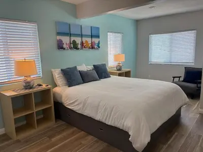 a bedroom with a large bed with blue walls and windows at 4BR Retreat - Pool Bar Play Area - Walk to Beach in Oceanside