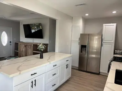 a kitchen with white cabinets and a stainless steel refrigerator at 4BR Retreat - Pool Bar Play Area - Walk to Beach in Oceanside