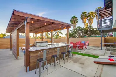 a patio with a bar with a grill and chairs at 4BR Retreat - Pool Bar Play Area - Walk to Beach in Oceanside