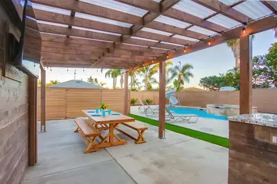 a patio with a wooden table and a pool at 4BR Retreat - Pool Bar Play Area - Walk to Beach in Oceanside