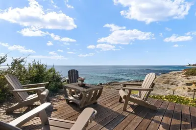 three chairs and a table on a deck overlooking the ocean at La Jolla Private Beach Oceanfront in San Diego