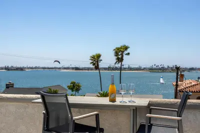 a table with two wine glasses and a view of the water at Pacific Beach Rooftop Views in San Diego